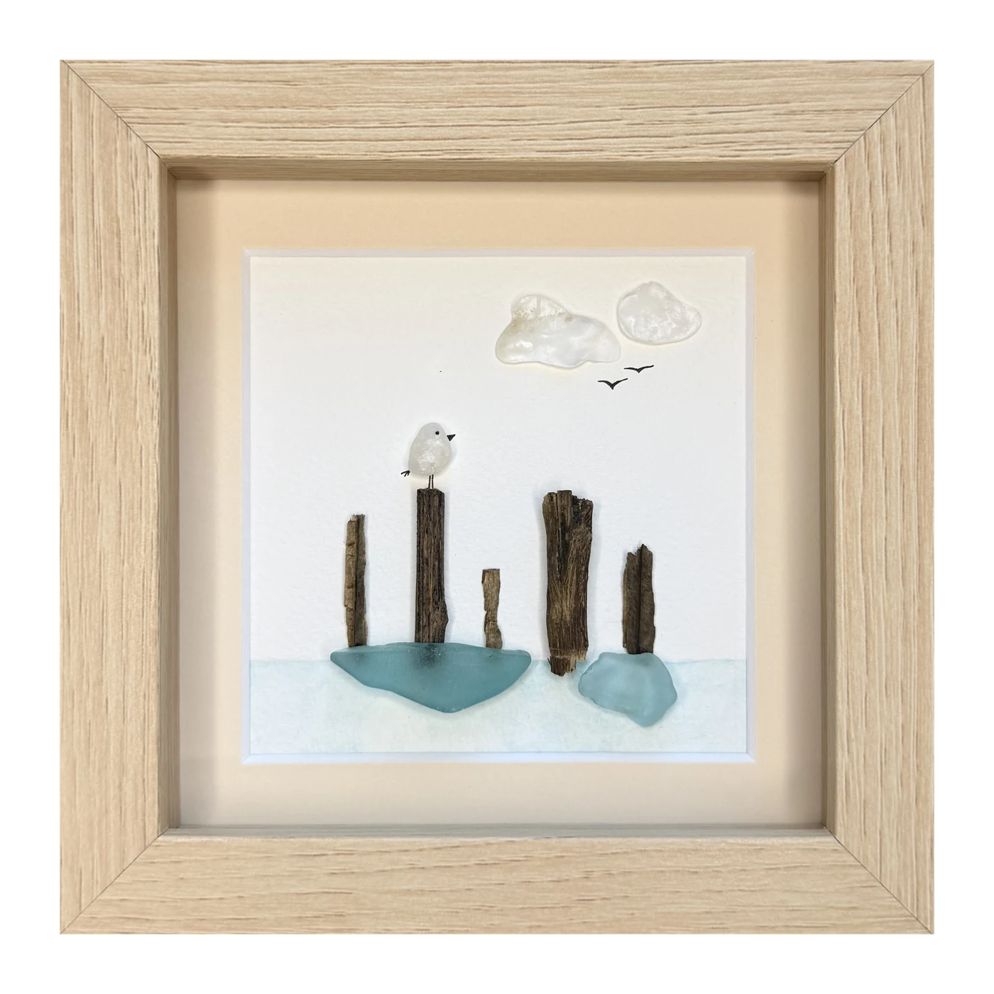 A white sea glass bird on driftwood pilings above pale green sea glass water