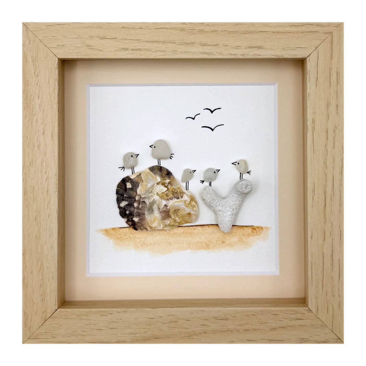 Five small stone birds on a shell and coral, with gulls overhead